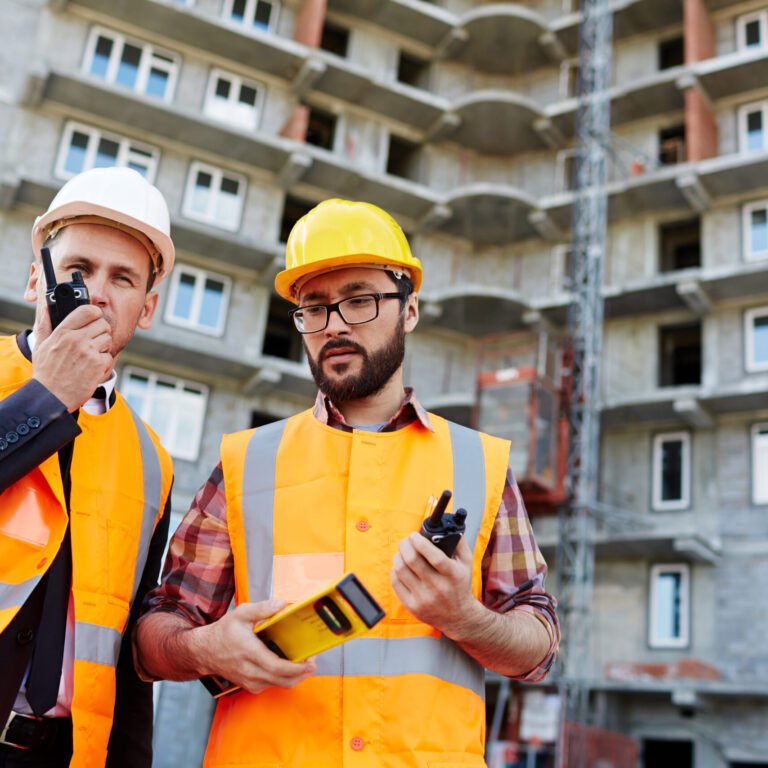Contractor speaking on walkie-talkie with colleague near by