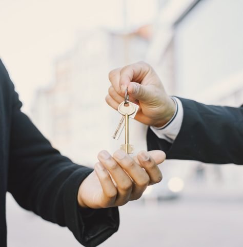 Property developer giving house keys to inmate Buying property concept. Man in uniform giving the keys to black man. Close up.
